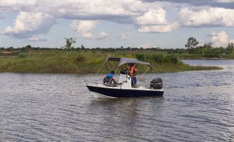 A man is standing on top of the water next to his boat, with people standing behind him at Kalipano Country Hotel