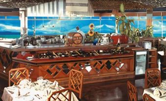 a dining room with a wooden bar , multiple chairs , and a painting on the wall at El Paseo Hotel