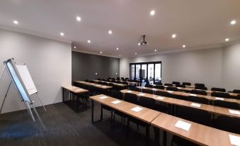 a conference room with rows of tables and chairs , a whiteboard , and a large window at Copperwood Hotel and Conferencing