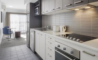 a modern kitchen with white cabinets and appliances , including a stove , oven , microwave , sink , and refrigerator at Quest Werribee