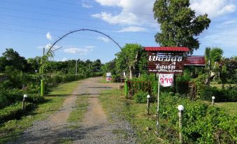 a dirt road leading to a house , with a sign indicating the name of the property at Piamsuk Resort