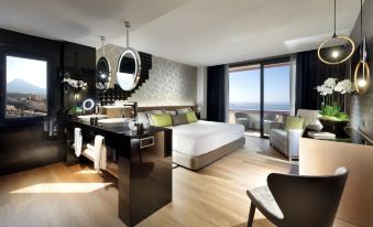 a modern bedroom with a large bed , desk , and chair , along with a view of the ocean at Hard Rock Hotel Tenerife
