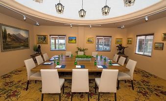 a conference room with a large table surrounded by chairs and surrounded by paintings on the walls at Hotel Mission de Oro