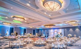 a large banquet hall with multiple round tables and chairs , chandeliers , and blue lighting , decorated for a wedding reception at Bethesda North Marriott Hotel & Conference Center