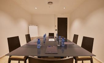 a conference room with a large table surrounded by chairs , water bottles , and a blank sign at Hotel Bristol 4 Sup