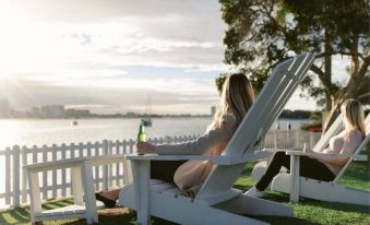 a woman is sitting on a white chair by the water , enjoying a drink while looking out at the ocean at Sea World Resort