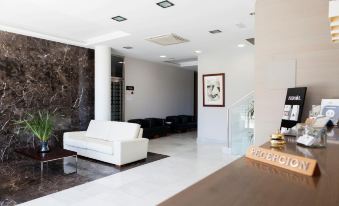 a modern living room with a white couch , marble wall , and wooden coffee table , connected to a staircase at Hotel Valencia