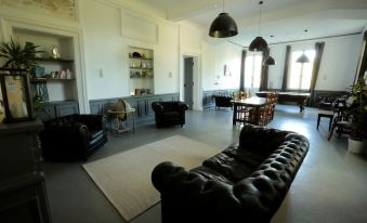 a spacious living room with a black leather couch , a dining table , and several chairs at Chateau Saint Martin B&B