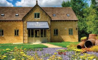 "a brick building with a sign that says "" cotswold "" and a flower garden in front" at The Crown Hotel