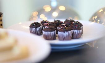 a white plate with several chocolate cupcakes topped with sprinkles , placed on a dining table at Golf Phu My Hotel