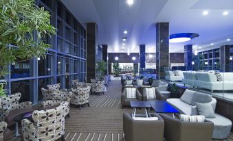 a large , well - lit room with multiple couches and chairs arranged in various positions , creating a comfortable seating area at Palm Wings Kusadasi Beach Resort&Spa