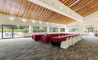 a large , open room with a wooden ceiling and walls , featuring rows of red tables and white chairs at Hotel Rancho San Diego Grand Spa Resort