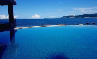 a large , blue swimming pool with a clear blue sky and ocean in the background at Hotel la Alondra