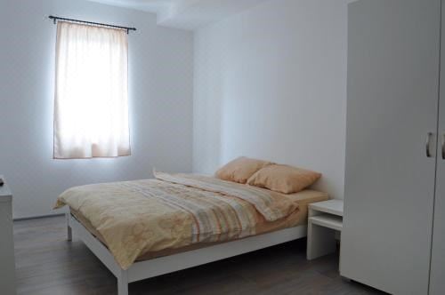 a clean and simple bedroom with a white bed , orange bedding , and a window with sheer curtains at Vanilla Rooms