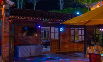 a brick building with a screened - in porch , surrounded by trees and lit up with colorful lights at night at Hotel la Perla