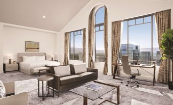 a modern living room with large windows , white walls , and a gray carpet , featuring a brown couch , coffee table , and other furniture at Signia by Hilton San Jose