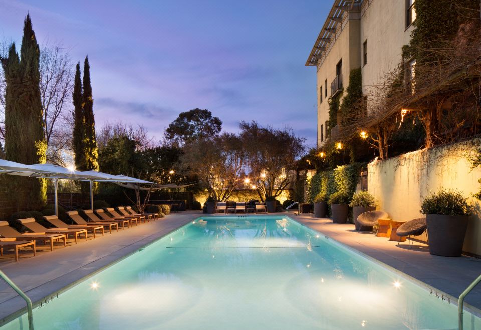 a large swimming pool with a row of lounge chairs and a building in the background at Hotel Healdsburg