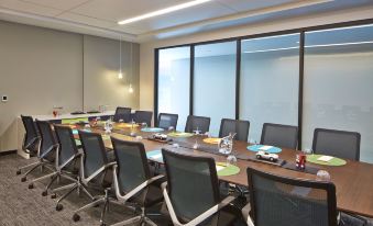 a conference room with a long wooden table surrounded by chairs , and a tv mounted on the wall at Aloft Seattle Redmond