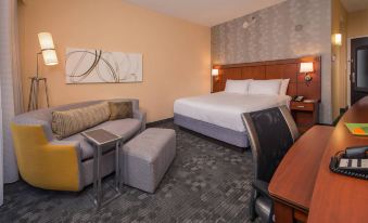 a hotel room with a king - sized bed , a couch , a desk , and a chair , all arranged in a modern style at Courtyard New Carrollton Landover