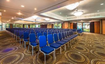 a large conference room with rows of blue chairs arranged in a semicircle , ready for an event at Holiday Inn London - Brentford Lock