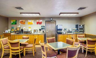 a restaurant with wooden tables and chairs , a counter with coffee machines , and colorful signs at Quality Inn