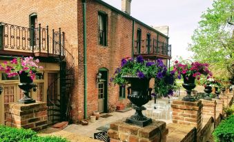 a brick house with a staircase leading to the second floor , surrounded by a garden filled with various plants and flowers at Iron Horse Hotel