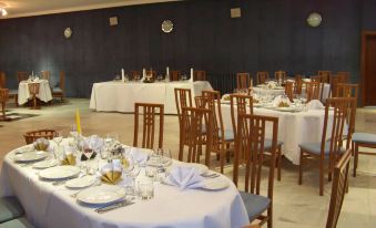 a dining room with tables set for a formal event , featuring white tablecloths and wooden chairs at Hotel Belvedere