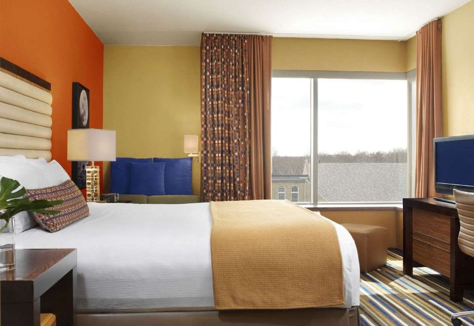 a large bed with a yellow blanket is in a room with orange walls and a window at The Moonrise Hotel