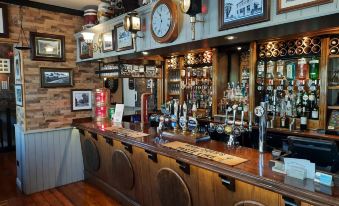 a traditional english pub with wooden furniture , various bottles of alcohol , and a clock on the wall at The Labouring Man