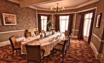 a formal dining room with a long table set for a dinner party , surrounded by elegant chairs at The Abbey