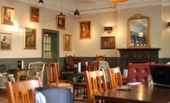 a dining room with wooden tables and chairs , a mirror on the wall , and paintings hanging on the wall at The Windmill