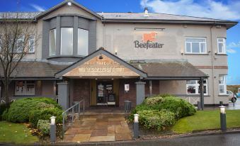 "a large building with a sign that says "" beefeater "" has several potted plants in front of it" at Premier Inn Glasgow (Motherwell)