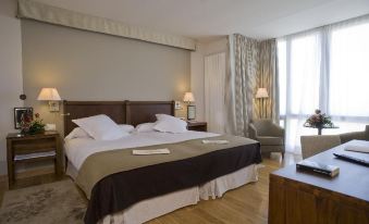 a large bed with white and brown linens is in a room with wooden floors and a window at Parador de Argomaniz