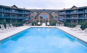 a large swimming pool is surrounded by lounge chairs and umbrellas , with a building in the background at Scandinavian Lodge