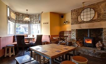 a cozy restaurant with wooden tables and chairs , a fireplace , and a window view of the outdoors at The Temple Inn