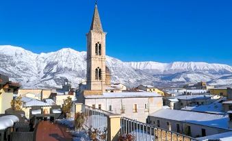 a picturesque town with a church in the center , surrounded by snow - covered mountains and a blue sky at Legacy