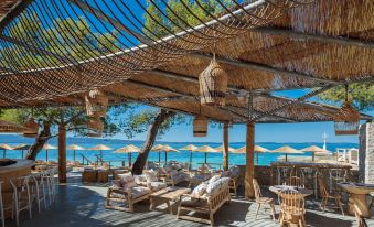 a beach bar with wooden tables and chairs , under a thatched roof , overlooking the ocean at Le Méridien Lav, Split