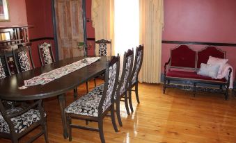a dining room with a wooden table and chairs , a red chair , and a pink wall at Copper House
