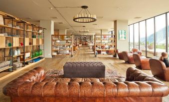 a large room with multiple couches and chairs , some of which are leather couches , arranged in a library setting at Rooms Hotel Kazbegi