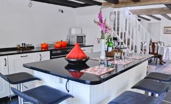 a modern kitchen with black countertops and white cabinets , featuring a red fruit bowl on the counter at The Who'd Have Thought It Inn