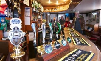 a bar with multiple beer taps and several people standing around it , enjoying the bar at King's Arms