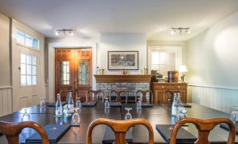 a dining room with a large wooden table , surrounded by chairs , and a fireplace in the background at The Little Inn of Bayfield