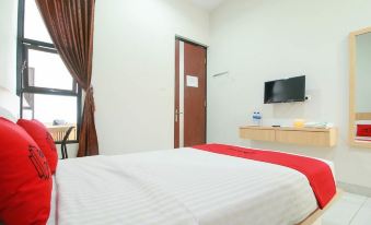 a clean and well - organized hotel room with a bed , a tv , and a bathroom at RedDoorz Syariah Near Universitas Jenderal Soedirman