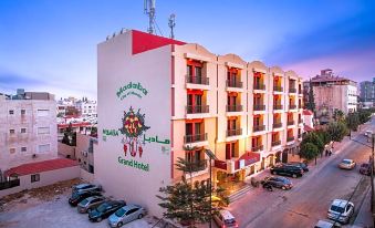 a large hotel building with a red and white color scheme , located in a city street at Grand Hotel Madaba