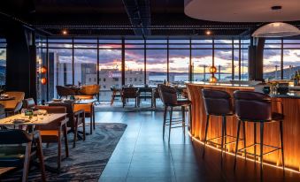 a modern restaurant with large windows , wooden tables and chairs , and a view of the ocean at Crowne Plaza Hobart, an IHG Hotel