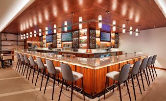a modern bar with wooden walls and a long wooden counter , featuring multiple televisions and chairs at San Mateo Marriott San Francisco Airport