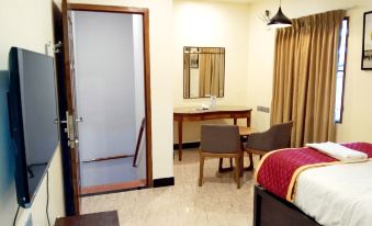 a hotel room with a bed , desk , and chair , as well as a bathroom door at Park Royale