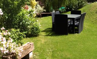 a lush green lawn with several black chairs and tables set up for outdoor dining , surrounded by flowers and trees at La Grange