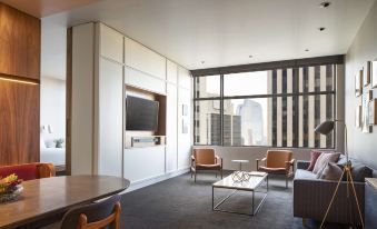 a modern living room with a large window , white walls , and wooden furniture , including two armchairs and a coffee table at Grand Hyatt Denver