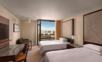 a hotel room with two twin beds , a desk , and a window overlooking a cityscape at Lisbon Marriott Hotel